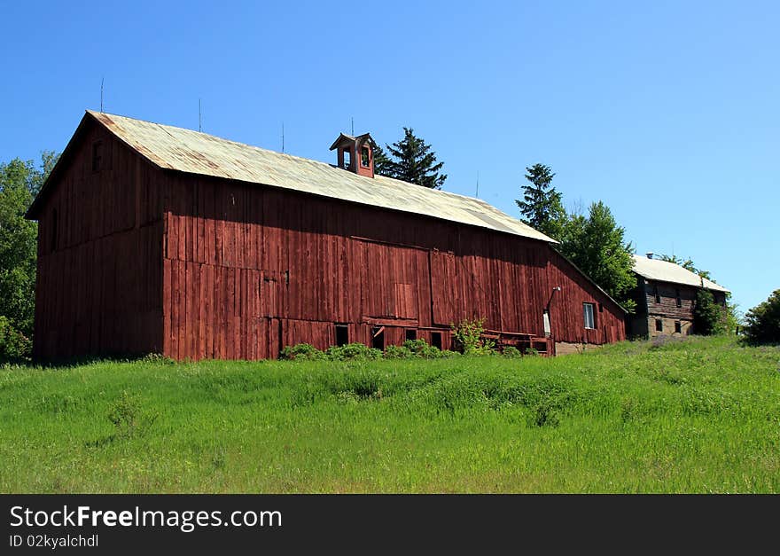 Long red barn with silver roof. Shed addition and another barn at far end. Long red barn with silver roof. Shed addition and another barn at far end.