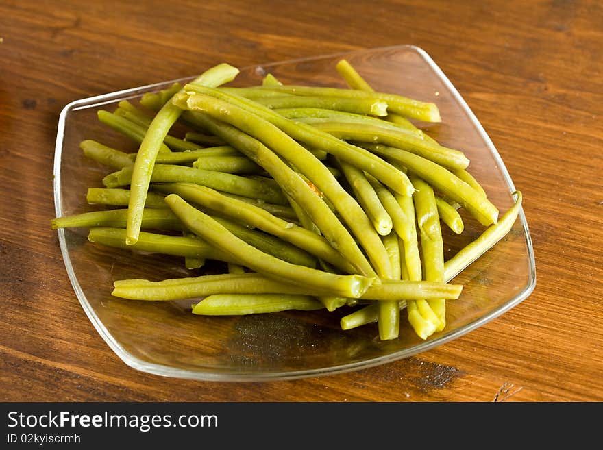 Photo of french beans on a glass platet putted on a wood table