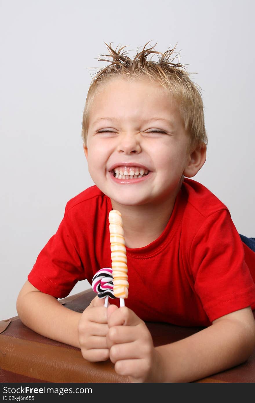 Young boy wearing a red shirt eating candy