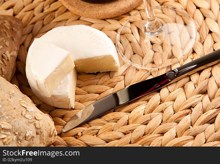 Wine picnic on grass with cheese, bread and other food.