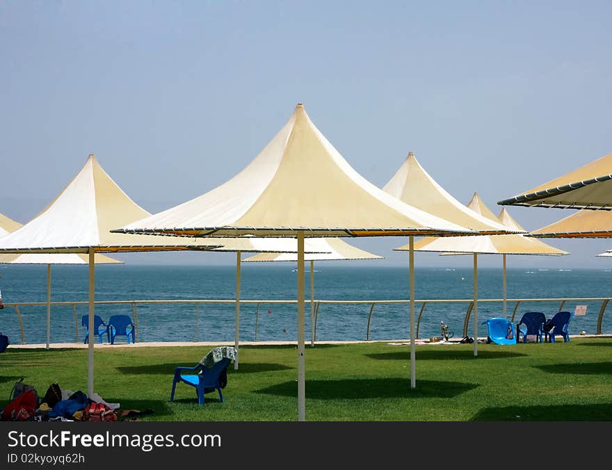 Beach view with colorful sunshade and green grass