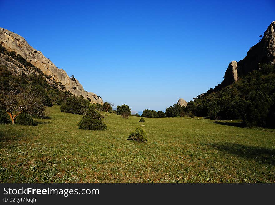 Mountain landscape east of crimea. The mountains and rocks, covered with juniper and pine. Blue sky. Mountain landscape east of crimea. The mountains and rocks, covered with juniper and pine. Blue sky