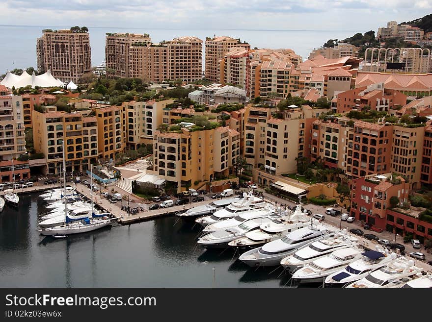 Mooring with yachts near many-storeyed buildings behind which the sea is visible. Mooring with yachts near many-storeyed buildings behind which the sea is visible