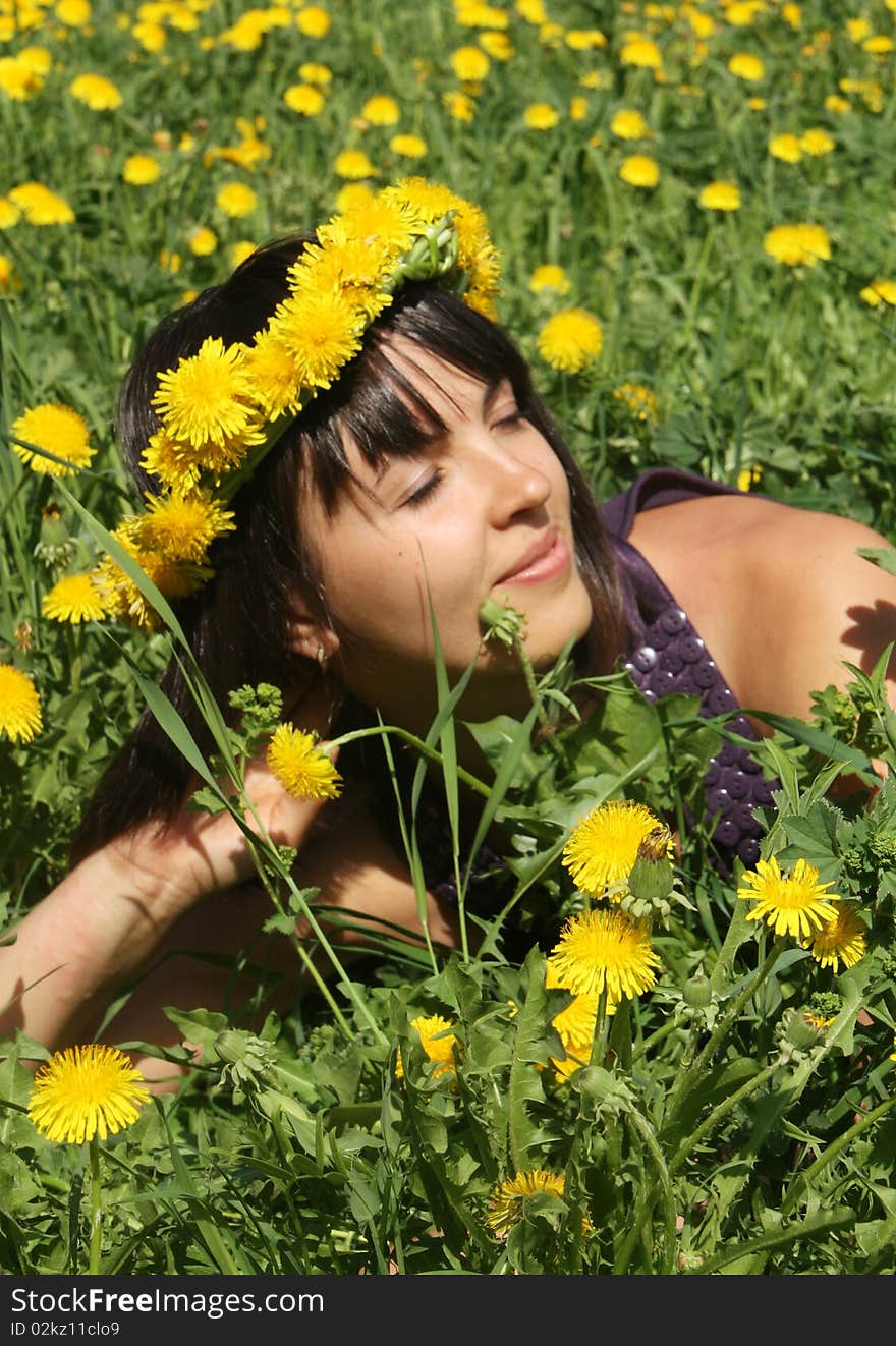 Attractive young woman smiling with a wreath of dandelions in flower meadow. Attractive young woman smiling with a wreath of dandelions in flower meadow