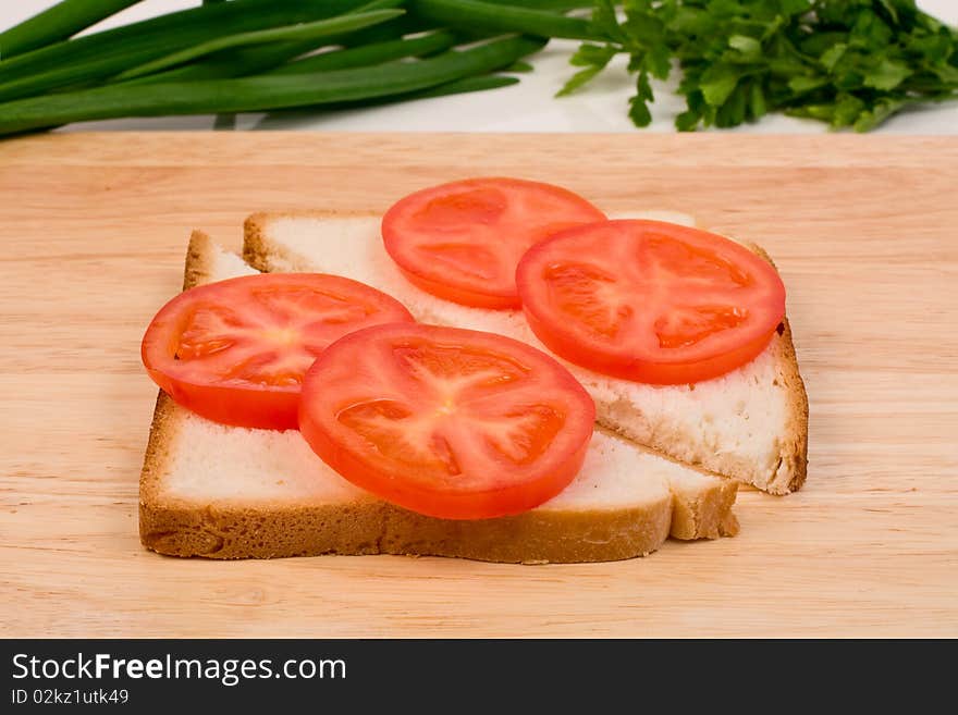 Cooking sandwich. Bread and tomato on a cutting board. Cooking sandwich. Bread and tomato on a cutting board