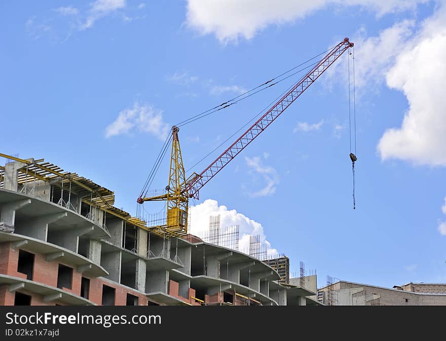 Building with elevating crane and clouds on background