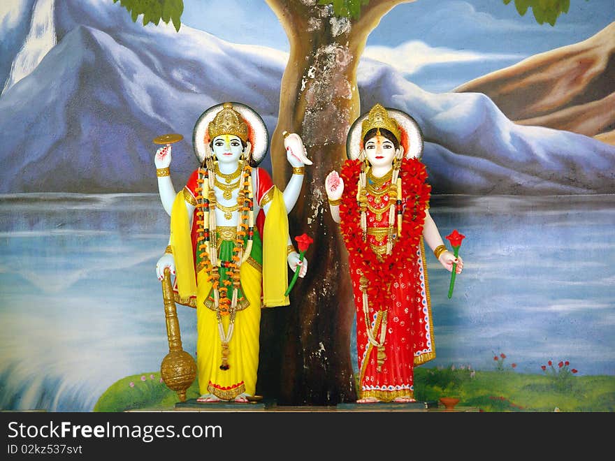 Lord Vishnu and goddess Lakshmi with hand-painted landscape background with water, rocks and mountains. Lord Vishnu and goddess Lakshmi with hand-painted landscape background with water, rocks and mountains