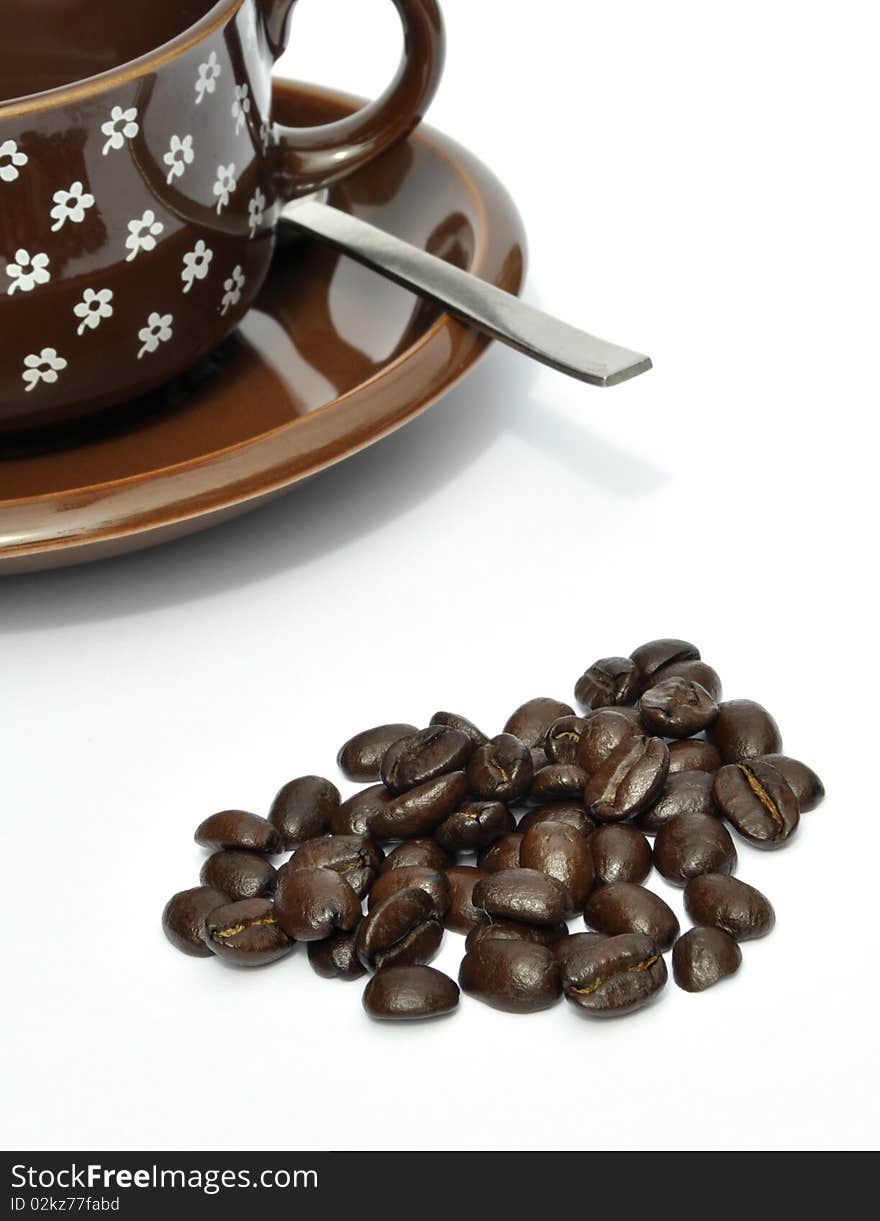 Coffee beans in foreground with cup and saucer. Coffee beans in foreground with cup and saucer