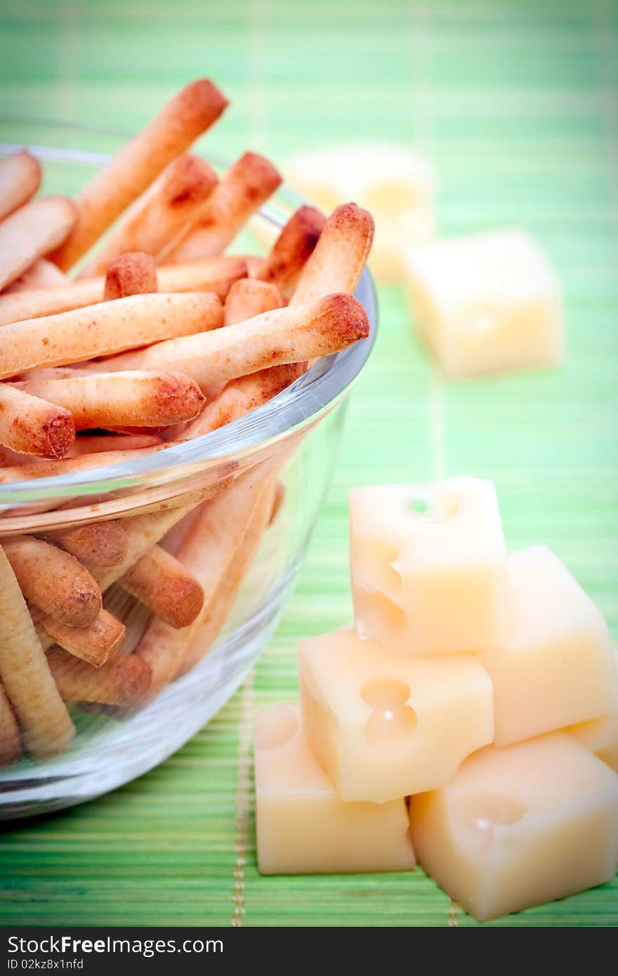 An assortment of bread sticks and cheese on a green bamboo mat. An assortment of bread sticks and cheese on a green bamboo mat