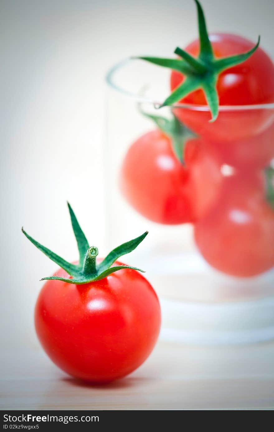 Whole cherry tomatoes in glass, on a bamboo mat. Whole cherry tomatoes in glass, on a bamboo mat.