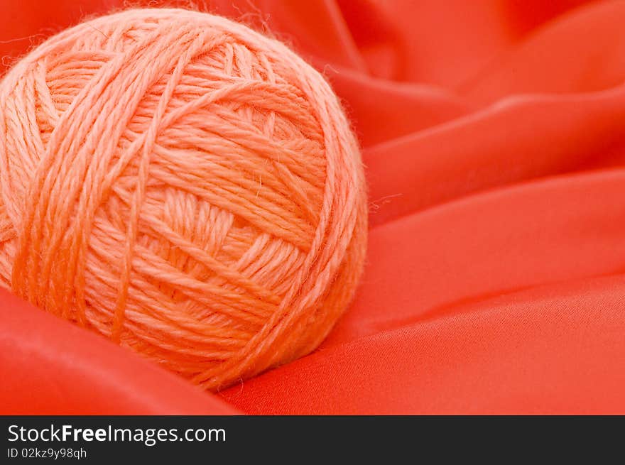 Ball of threads on a red fabric close up