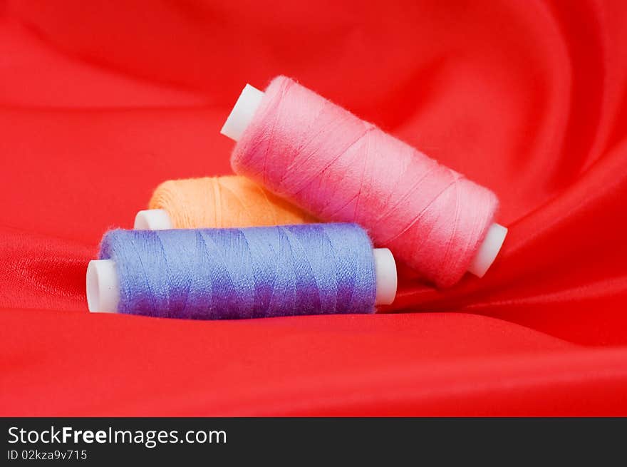 Ball of threads on a red fabric close up