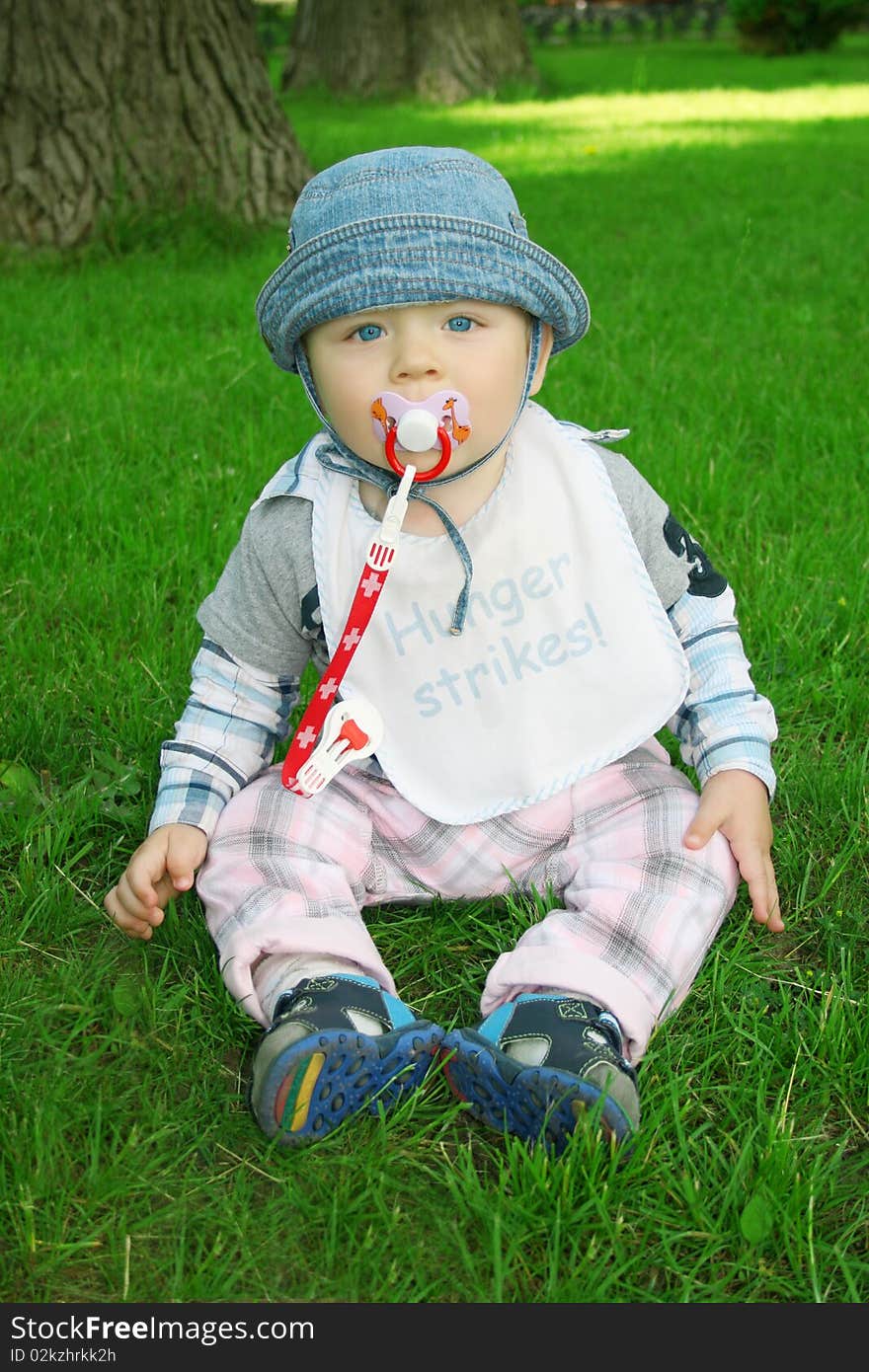 The boy the child sits on a grass in park. The boy the child sits on a grass in park