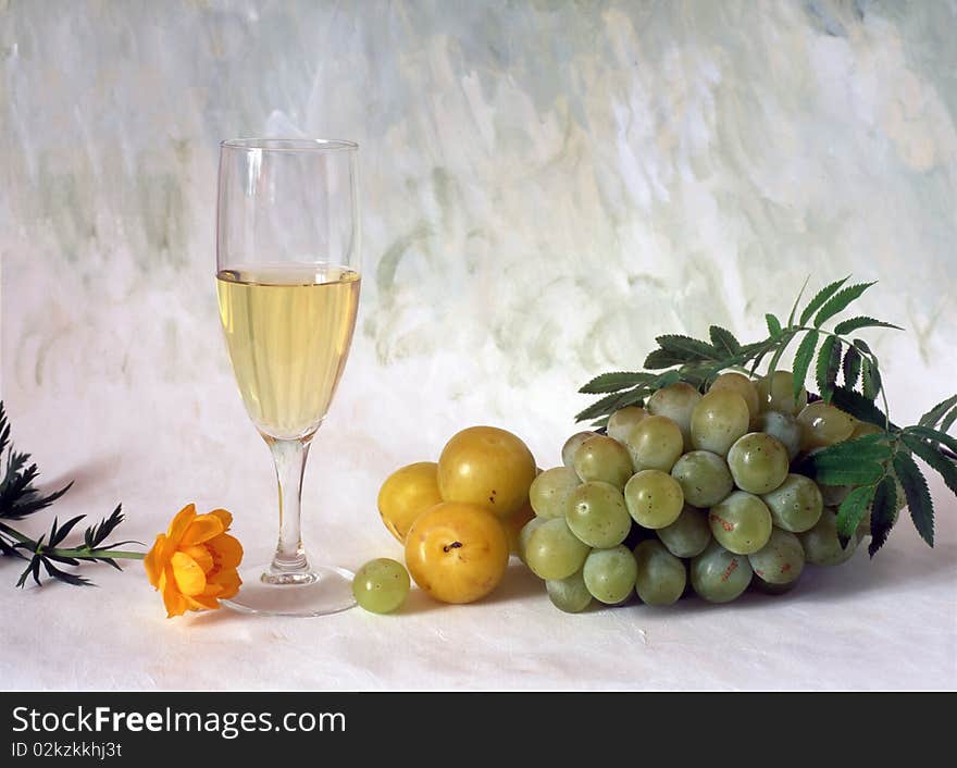 A glass of white wine with grapes isolated on painted background. A glass of white wine with grapes isolated on painted background