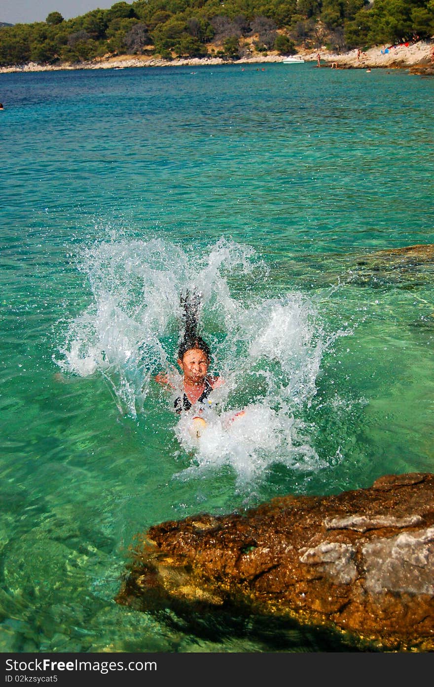 A young girl is jumping into adriatic water