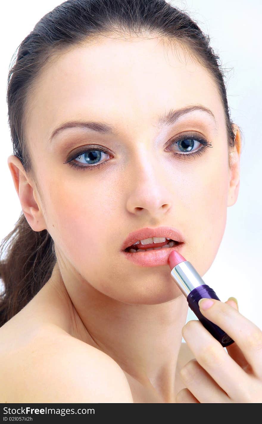 Portrait of beautiful woman applying lipstick