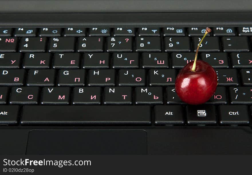 Blackenning keyboard of the computer and ripe berry to sweet cherrieses