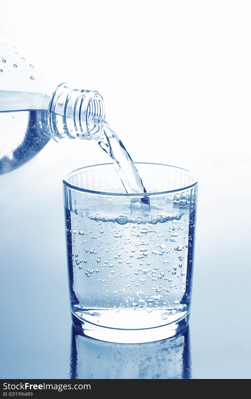 Water pouring into glass. toned blue.