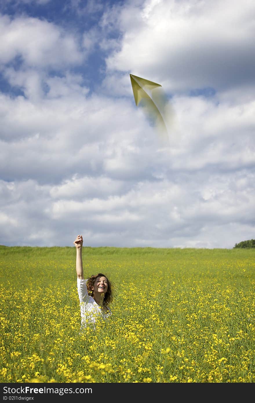 Woman In Rapeseed Field Throwing A Paper Plane