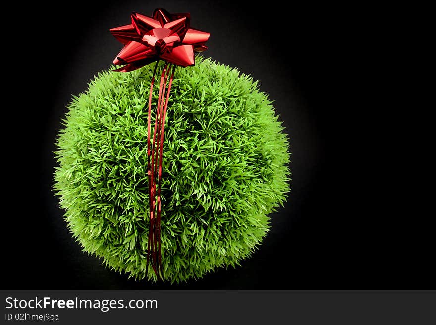 Green grass ball with red bow and ribbon over it, a gift fot the earth. Green grass ball with red bow and ribbon over it, a gift fot the earth