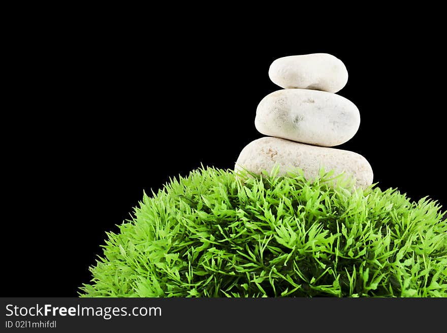 Three stones over a grass plastic ball, isolated on black. Three stones over a grass plastic ball, isolated on black