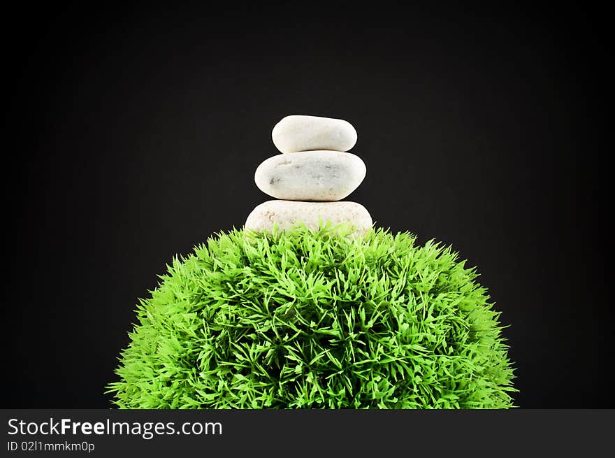 Three stones over a grass plastic ball, isolated on black. Three stones over a grass plastic ball, isolated on black