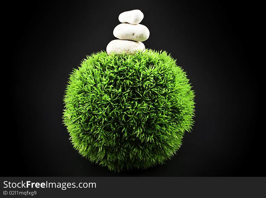 Three stones over a grass plastic ball, isolated on black. Three stones over a grass plastic ball, isolated on black