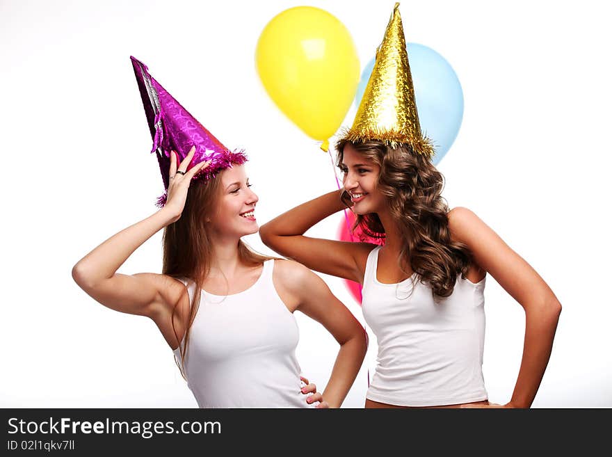 Two young girlfriends in holiday caps with color balloons. Two young girlfriends in holiday caps with color balloons