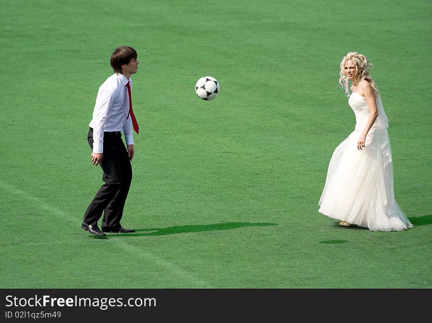 Young wedding couple playing football on the green field. Young wedding couple playing football on the green field