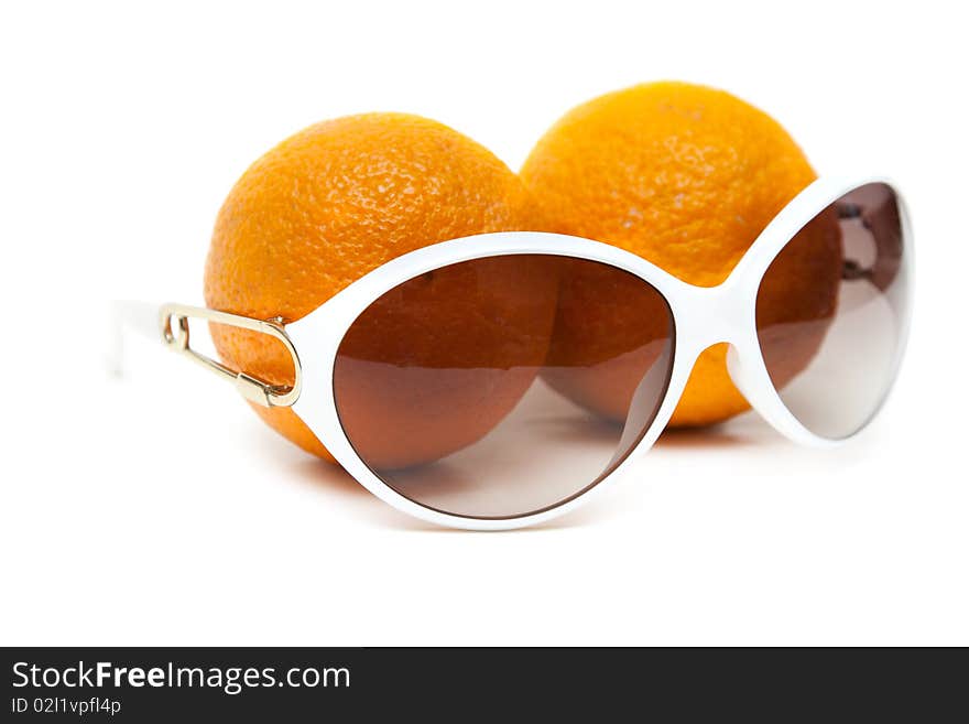 Sunglasses and two oranges on white background