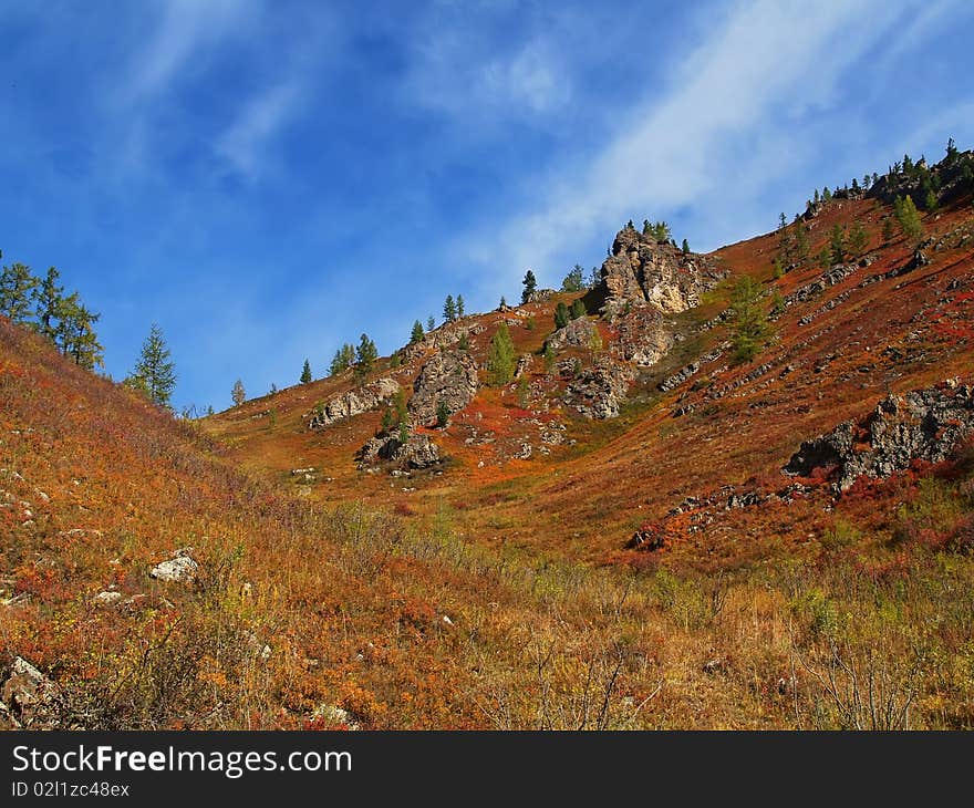 Red mountains with dry grass, sky with clouds