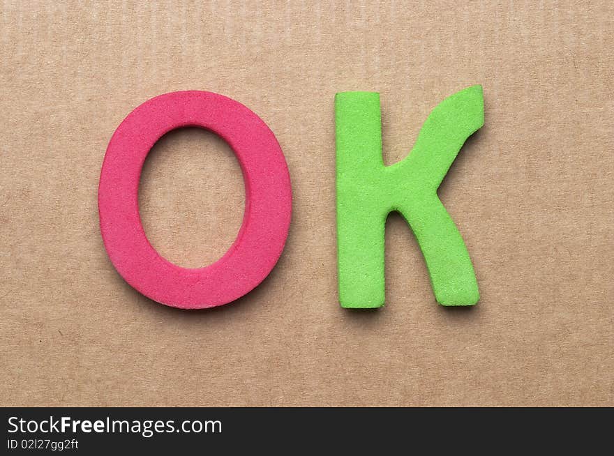 3D Plastic OK letters over cardboard background macro shot