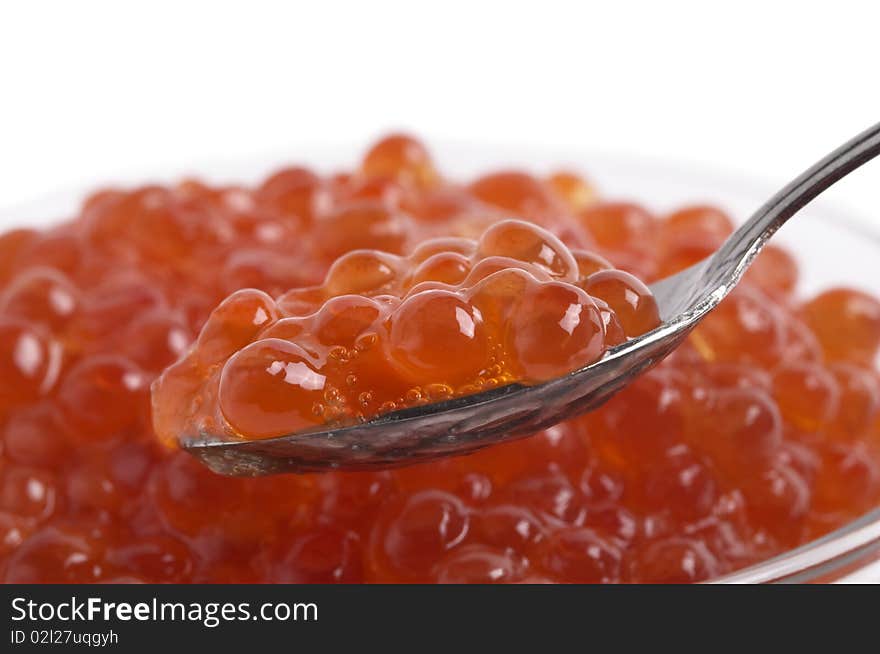 Red caviar in the little glass bow and spoon fragment isolated over white background