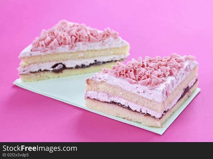 Close up of fresh sliced cake on pink table top