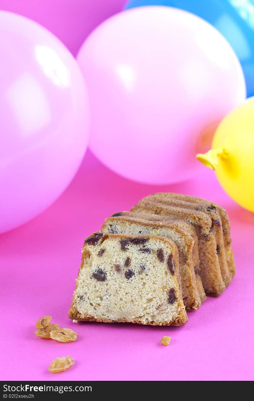 Close up of fresh cake on pink table top with some balloon on the background