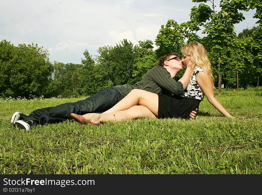 Young man and girl kissing outdoor at summer lawn