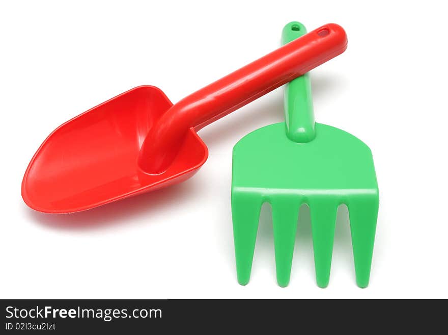 Toy red shovel and green rake isolated on white background