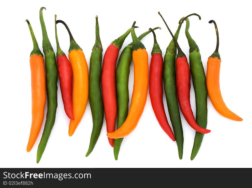 Mixed coloured chilli peppers on a white background