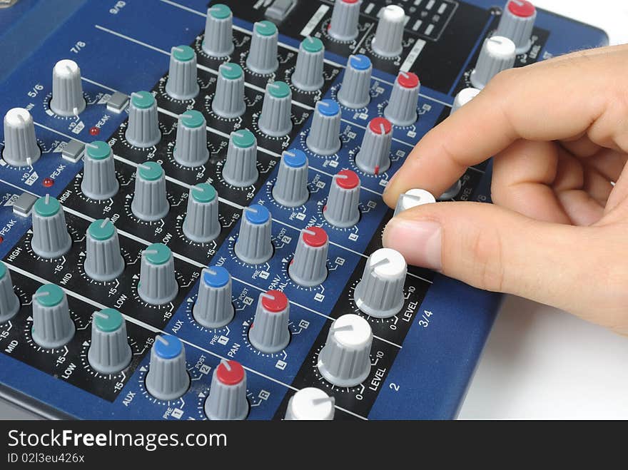 A and twisting a knob on a mixing board of a preamp. A and twisting a knob on a mixing board of a preamp.