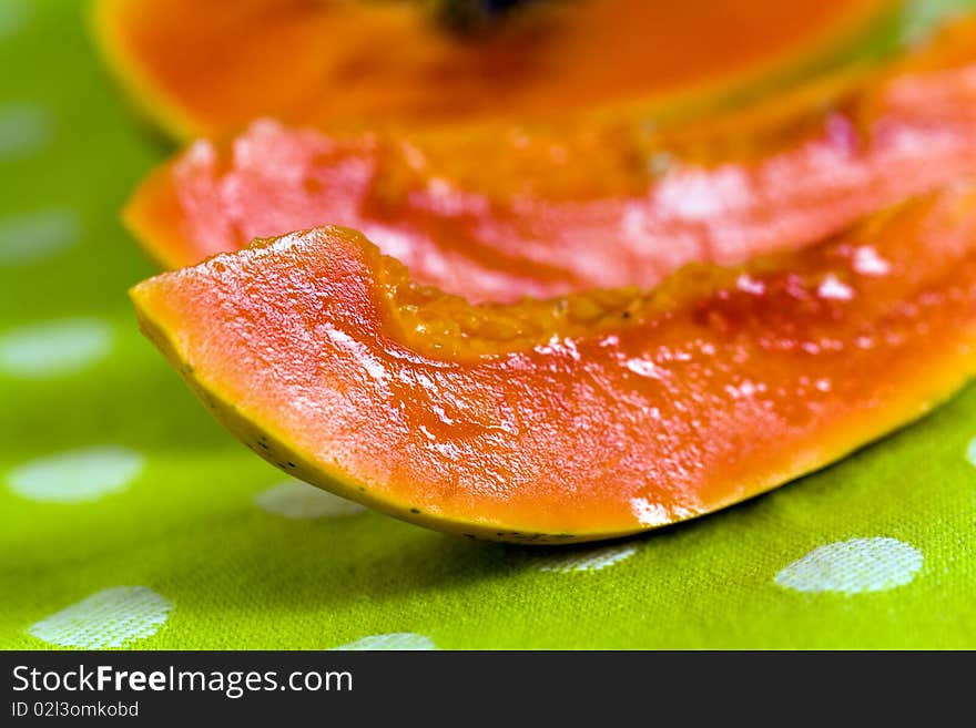 Cut up papaya fruit on green background