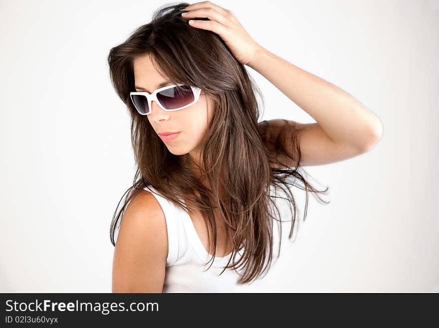 A young woman in a white tank top and white sunglasses, looking fashionable. A young woman in a white tank top and white sunglasses, looking fashionable