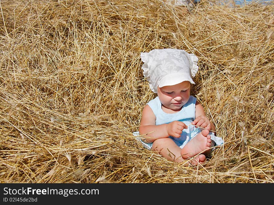 Toddler girl playing in haystack