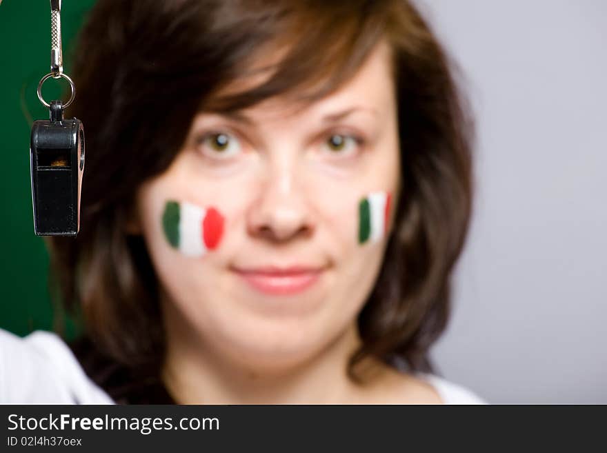 Black whistle on foreground with female face being blurres as background, italian flags painted on female cheeks. Black whistle on foreground with female face being blurres as background, italian flags painted on female cheeks