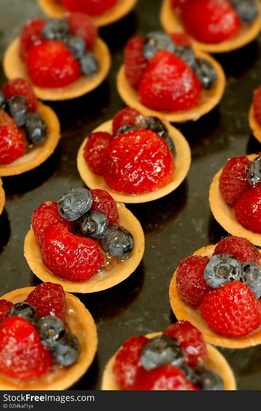 Strawberry and blueberry tarts are in rows.