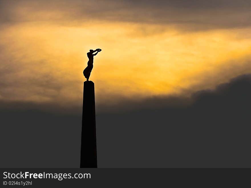 Monument in the Constitution Place in Luxembourg, commemorating the Luxembourgers who died during the First World War. The monument is known as `Gelle Fra` (Golden Lady). The picture was taken at sunset and the resulting dark construction is intentional. Monument in the Constitution Place in Luxembourg, commemorating the Luxembourgers who died during the First World War. The monument is known as `Gelle Fra` (Golden Lady). The picture was taken at sunset and the resulting dark construction is intentional.