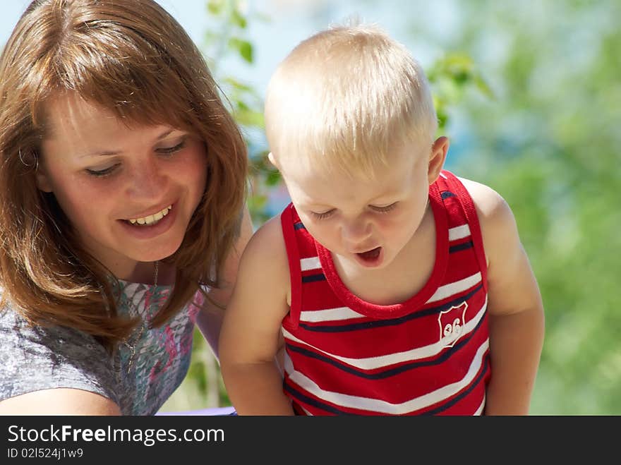 Young mum with the son on a background of green plants in the summer. Young mum with the son on a background of green plants in the summer