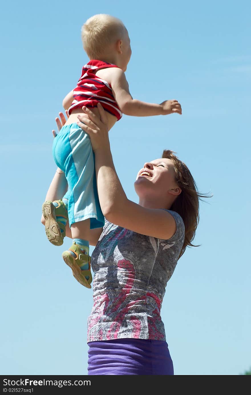 Mum with the small son on hands on a background of the dark blue sky. Mum with the small son on hands on a background of the dark blue sky