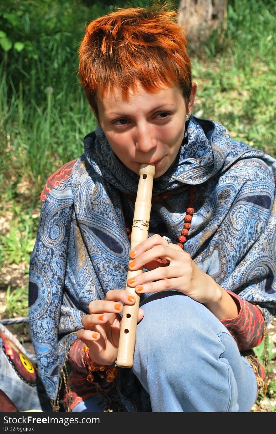 Young woman playing wooden reed on grass. Young woman playing wooden reed on grass