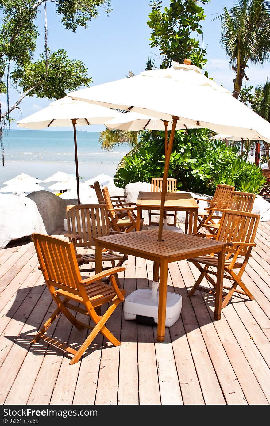 The cue wooden chairs under the pale white umbrella.