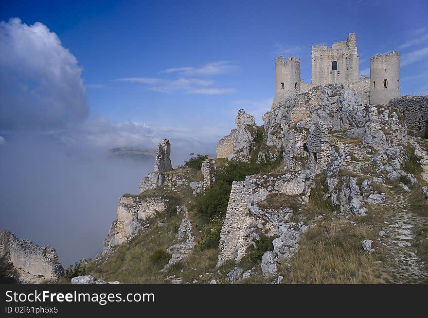 A castle in ruin on top of a mountain in central Italy.
The mountain is surrounded by clouds. A castle in ruin on top of a mountain in central Italy.
The mountain is surrounded by clouds.